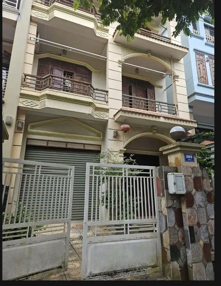 Ảnh hiện trạng — Mặt tiền hiện trạng: hệ cổng, ban công, cửa và các đường phào của ngôi nhà.