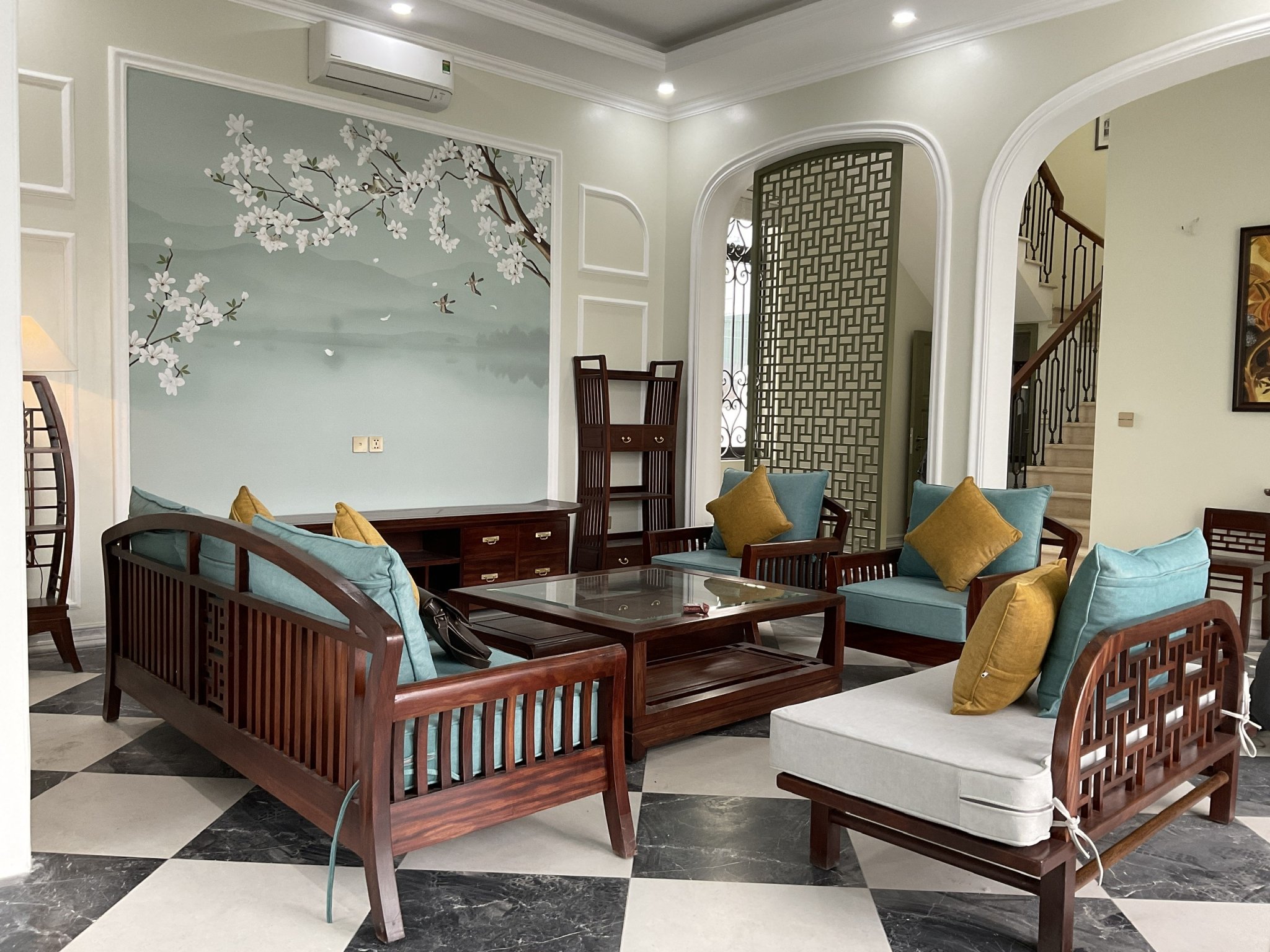 Không gian phòng khách với nội thất gỗ tự nhiên, đệm xanh và tranh tường — Bois Indochinois